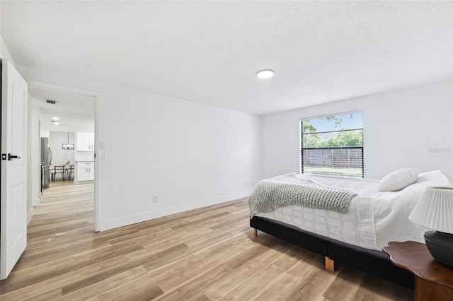 622 Cedar Grove Dr, Brandon, FL 33511 - bedroom with light wood finished floors, freestanding refrigerator, a textured ceiling, and baseboards