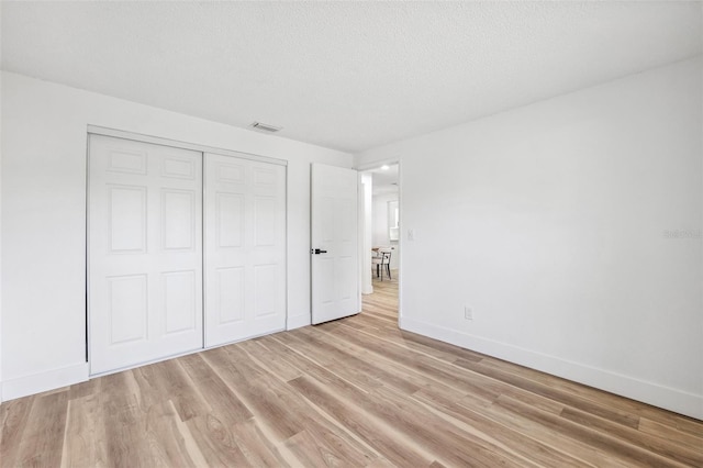 622 Cedar Grove Dr, Brandon, FL 33511 - unfurnished bedroom with light wood-style floors, baseboards, a closet, and a textured ceiling