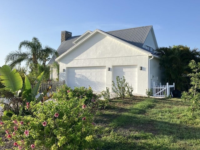 14510 Mj Rd, Myakka City, FL 34251 - view of side of property with stucco siding, a garage, and a chimney