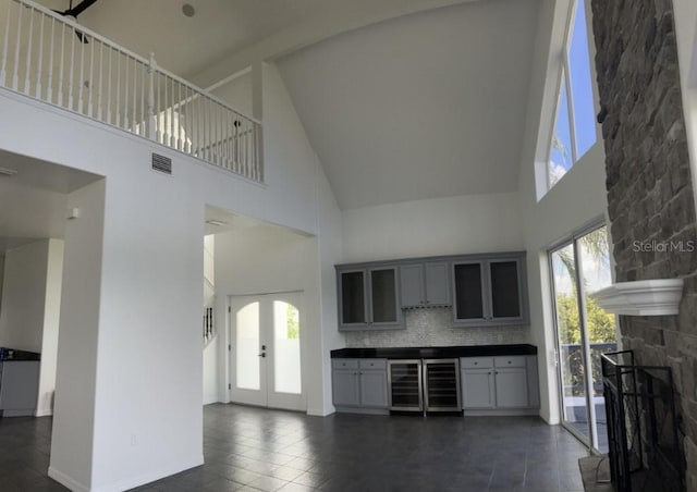 14510 Mj Rd, Myakka City, FL 34251 - unfurnished living room featuring high vaulted ceiling, french doors, healthy amount of natural light, a stone fireplace, and wine cooler