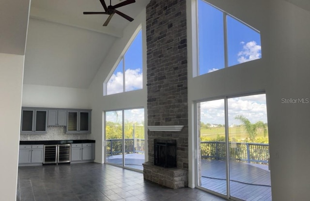 14510 Mj Rd, Myakka City, FL 34251 - unfurnished living room featuring high vaulted ceiling, ceiling fan, wine cooler, a stone fireplace, and dark tile patterned floors