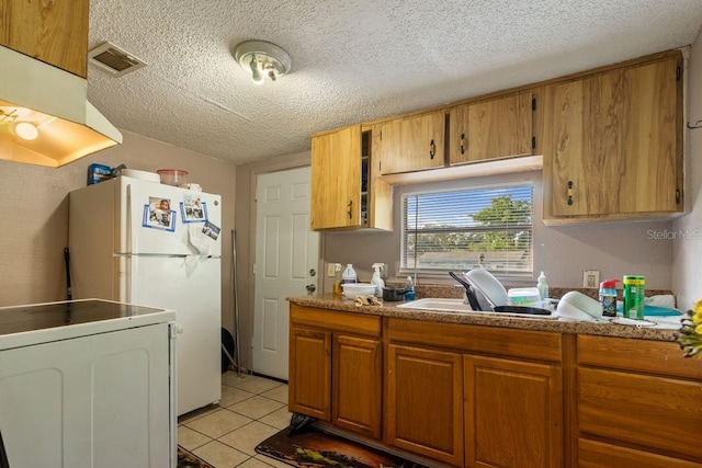 1224 S Delaware Ave, Deland, FL 32720 - kitchen with a textured ceiling, freestanding refrigerator, ventilation hood, brown cabinetry, and light tile patterned floors
