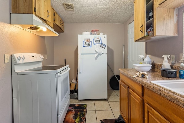 1224 S Delaware Ave, Deland, FL 32720 - kitchen with white appliances, under cabinet range hood, light tile patterned floors, brown cabinetry, and a textured ceiling