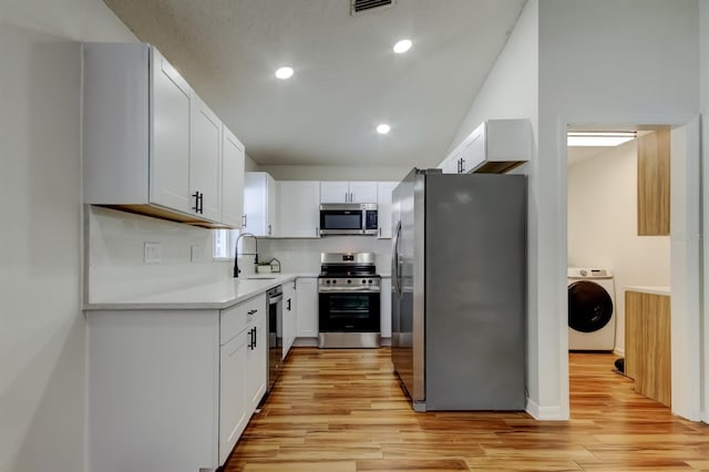 5435 Birchwood Rd, Spring Hill, FL 34608 - kitchen featuring stainless steel appliances, washer / dryer, a sink, light wood-style floors, and light countertops