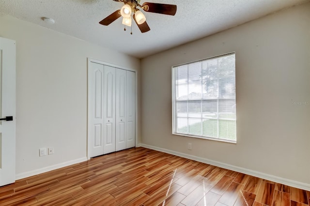 5435 Birchwood Rd, Spring Hill, FL 34608 - unfurnished bedroom with wood finish floors, a closet, baseboards, a textured ceiling, and ceiling fan