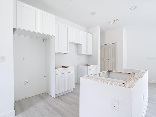 16134 Libourn Ave, Port Charlotte, FL 33954 - kitchen with a kitchen island, white cabinets, and light wood-style floors