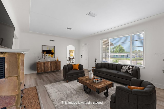 2449 16th St N, Saint Petersburg, FL 33704 - living room with arched walkways, wood finished floors, a fireplace with flush hearth, and baseboards
