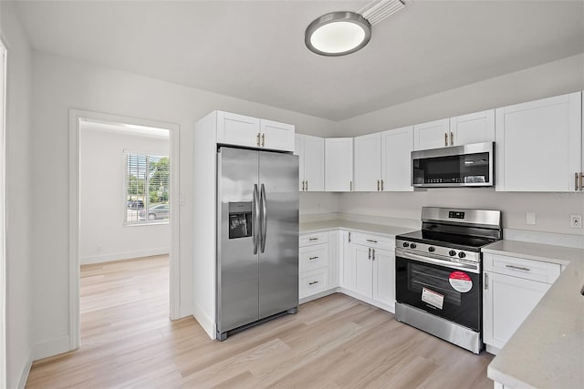2449 16th St N, Saint Petersburg, FL 33704 - kitchen featuring stainless steel appliances, light wood-style floors, white cabinetry, and baseboards
