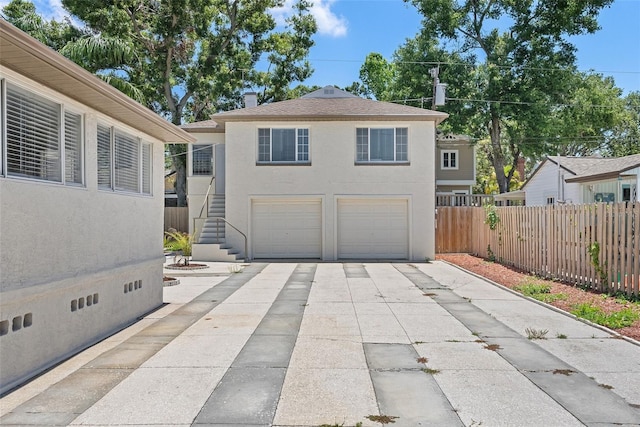 2449 16th St N, Saint Petersburg, FL 33704 - rear view of house featuring stucco siding, concrete driveway, an attached garage, stairway, and a shingled roof