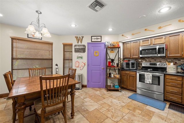 717 E 137th Ave, Tampa, FL 33613 - kitchen featuring stainless steel appliances, dark countertops, decorative backsplash, stone tile flooring, and a chandelier