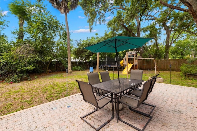 717 E 137th Ave, Tampa, FL 33613 - view of patio / terrace featuring a trampoline, a playground, and outdoor dining space