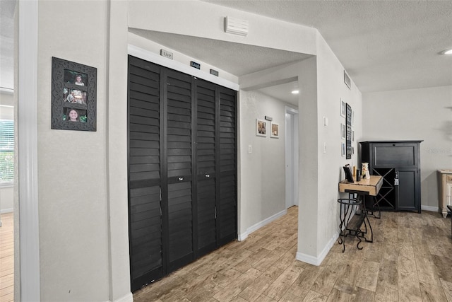 7304 Lakeside Blvd, Tampa, FL 33614 - hallway featuring light wood-style floors, a textured ceiling, and baseboards
