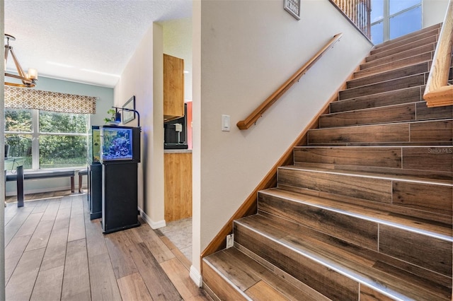 1611 County Road 753s, Webster, FL 33597 - staircase featuring a chandelier, hardwood / wood-style flooring, baseboards, a textured ceiling, and vaulted ceiling