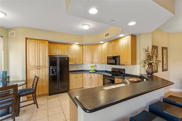 521 Mandalay Ave Unit 307, Clearwater Beach, FL 33767 - kitchen featuring black appliances, dark countertops, light brown cabinets, a peninsula, and a sink