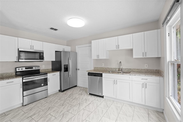 6489 30th St N, Saint Petersburg, FL 33702 - kitchen featuring stainless steel appliances, a sink, white cabinets, light stone countertops, and light marble finish flooring