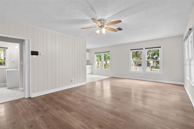 6489 30th St N, Saint Petersburg, FL 33702 - unfurnished living room with light wood-type flooring, ceiling fan, baseboards, and a textured ceiling