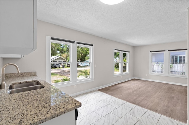 6489 30th St N, Saint Petersburg, FL 33702 - kitchen featuring a sink, light stone counters, baseboards, a textured ceiling, and light marble finish floors