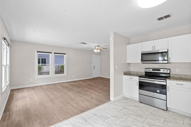 6489 30th St N, Saint Petersburg, FL 33702 - kitchen with appliances with stainless steel finishes, a ceiling fan, white cabinets, open floor plan, and light stone countertops