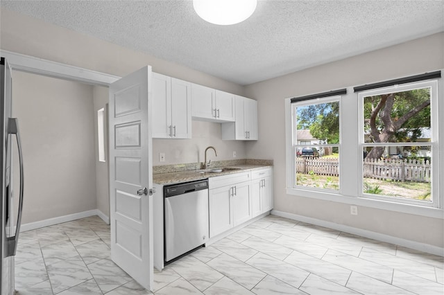 6489 30th St N, Saint Petersburg, FL 33702 - kitchen with appliances with stainless steel finishes, a sink, light marble finish flooring, light stone counters, and white cabinets