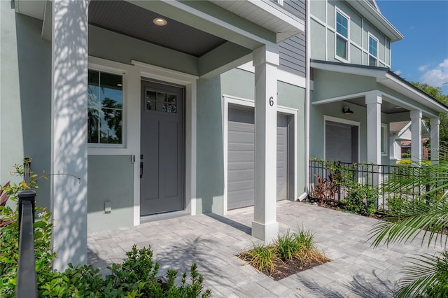 5530 N 9th St Unit 6, Tampa, FL 33604 - doorway to property featuring stucco siding, covered porch, and a garage