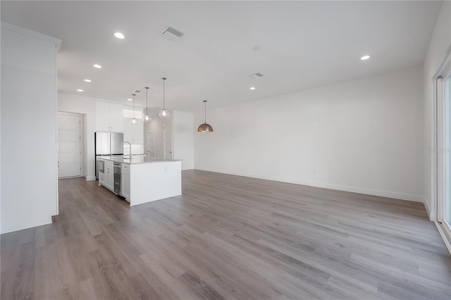5530 N 9th St Unit 6, Tampa, FL 33604 - kitchen with white cabinetry, a kitchen island with sink, recessed lighting, wood finished floors, and open floor plan