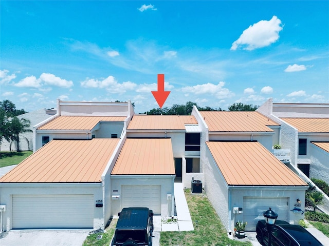 4360 Outrigger Ln, Tampa, FL 33615 - view of front of house with a standing seam roof, stucco siding, metal roof, a garage, and central AC
