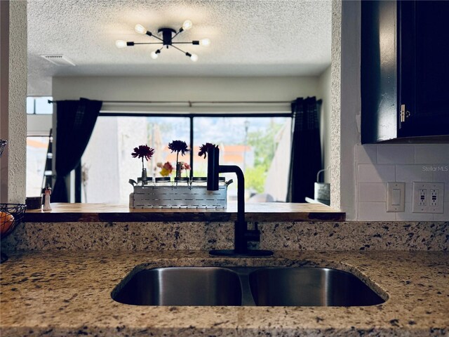 4360 Outrigger Ln, Tampa, FL 33615 - kitchen with a sink, a textured ceiling, light stone countertops, and backsplash