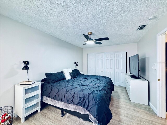 4360 Outrigger Ln, Tampa, FL 33615 - bedroom with light wood-style floors, a closet, a textured ceiling, and a ceiling fan