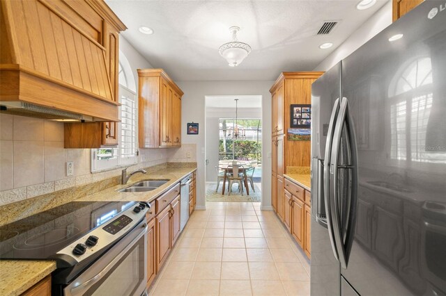 8708 Laurel Dr N, Pinellas Park, FL 33782 - kitchen featuring appliances with stainless steel finishes, a sink, premium range hood, backsplash, and light stone counters