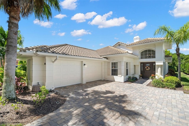 8708 Laurel Dr N, Pinellas Park, FL 33782 - mediterranean / spanish-style house with a tile roof, an attached garage, a chimney, decorative driveway, and stucco siding