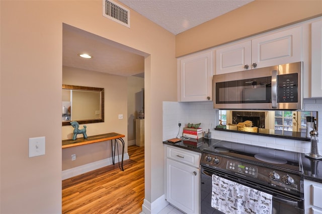 3053 S Concordia Ave Unit A, Tampa, FL 33629 - kitchen featuring stainless steel microwave, black range with electric cooktop, white cabinets, tasteful backsplash, and a textured ceiling