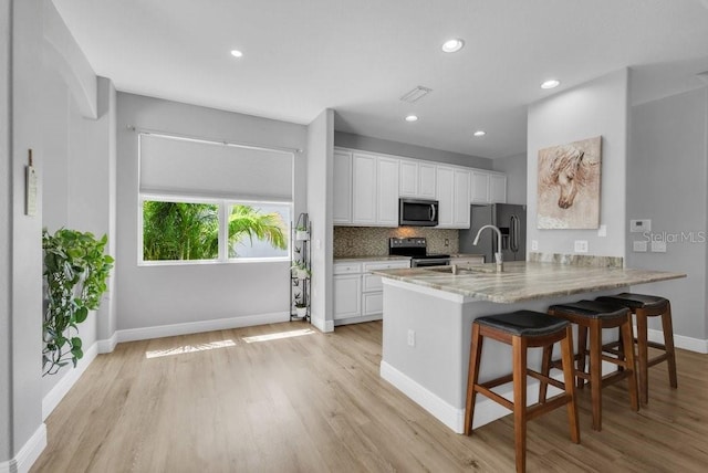 8223 Haven Harbour Way, Bradenton, FL 34212 - kitchen featuring appliances with stainless steel finishes, light wood-style floors, a peninsula, white cabinets, and recessed lighting