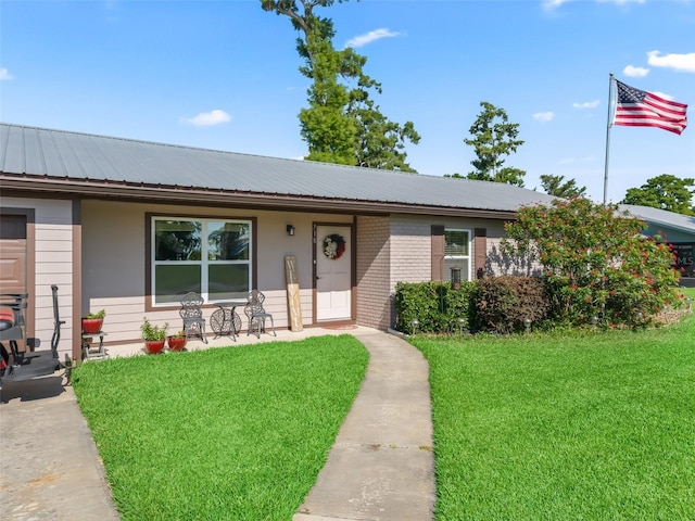 718 Crk 467, Lake Panasoffkee, FL 33538 - ranch-style house featuring a front yard, a porch, metal roof, and brick siding