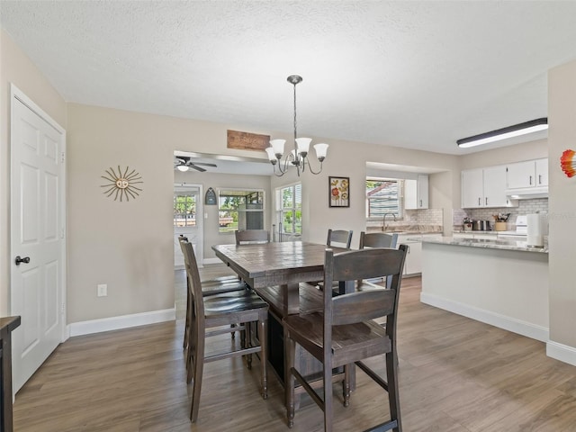 718 Crk 467, Lake Panasoffkee, FL 33538 - dining room with light wood-style flooring, a chandelier, ceiling fan, baseboards, and a textured ceiling