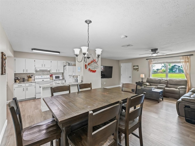 718 Crk 467, Lake Panasoffkee, FL 33538 - dining area with a textured ceiling, light wood-style floors, a chandelier, and a ceiling fan