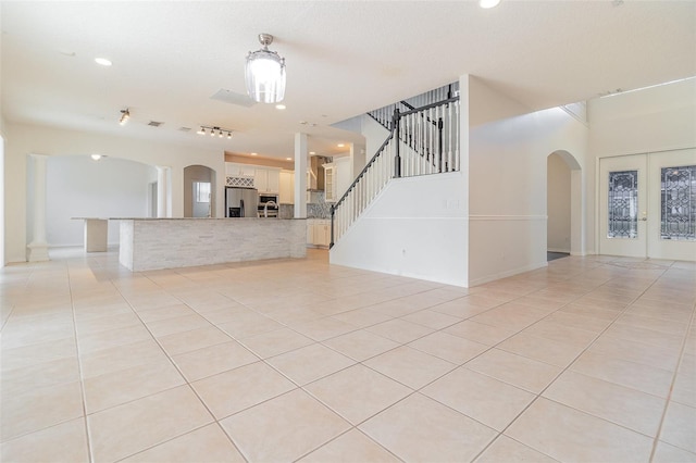 239 Beacon Pointe Dr, Ocoee, FL 34761 - unfurnished living room with arched walkways, light tile patterned floors, stairs, ornate columns, and recessed lighting