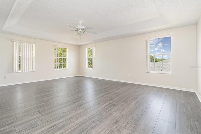 239 Beacon Pointe Dr, Ocoee, FL 34761 - unfurnished room with a raised ceiling, ceiling fan, a textured ceiling, dark wood-style flooring, and baseboards