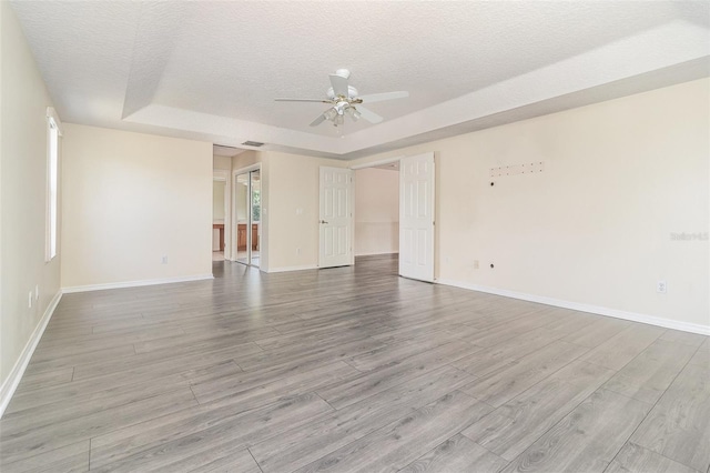 239 Beacon Pointe Dr, Ocoee, FL 34761 - spare room featuring a tray ceiling, wood finished floors, ceiling fan, a textured ceiling, and baseboards