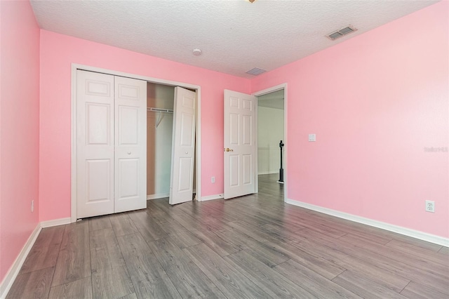 239 Beacon Pointe Dr, Ocoee, FL 34761 - unfurnished bedroom featuring wood finished floors, baseboards, a closet, and a textured ceiling