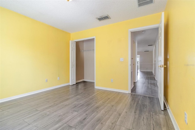 239 Beacon Pointe Dr, Ocoee, FL 34761 - unfurnished bedroom with wood finished floors, a textured ceiling, baseboards, and a closet