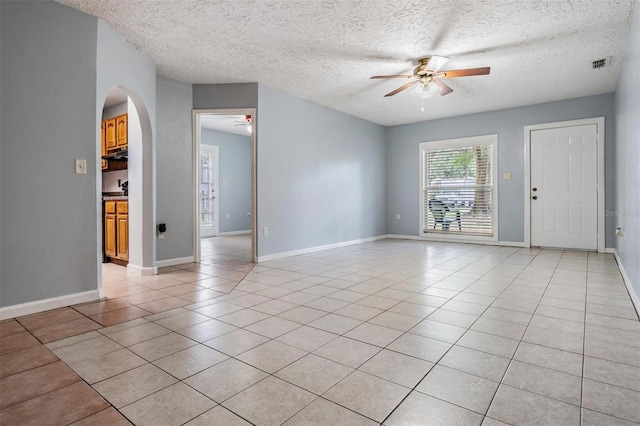 7347 Pulsar St, New Port Richey, FL 34652 - empty room featuring ceiling fan, arched walkways, light tile patterned floors, a textured ceiling, and baseboards