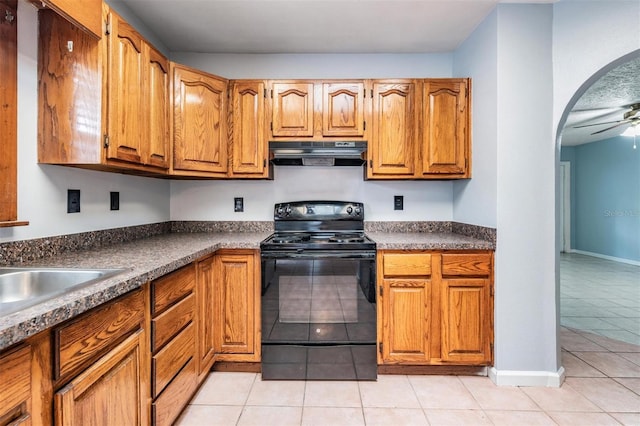 7347 Pulsar St, New Port Richey, FL 34652 - kitchen with under cabinet range hood, black / electric stove, arched walkways, light tile patterned floors, and brown cabinetry