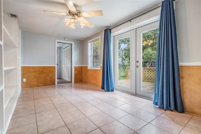 7347 Pulsar St, New Port Richey, FL 34652 - spare room with a wainscoted wall, french doors, plenty of natural light, a ceiling fan, and wood walls