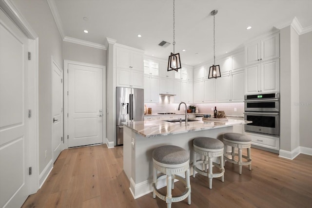 12 Country Club Ln, Belleair, FL 33756 - kitchen with stainless steel appliances, a sink, white cabinets, light wood-style floors, and crown molding