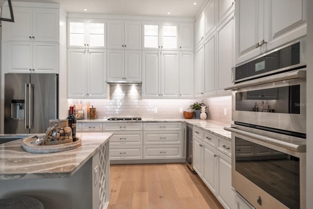 12 Country Club Ln, Belleair, FL 33756 - kitchen with appliances with stainless steel finishes, white cabinets, light stone countertops, light wood-type flooring, and recessed lighting