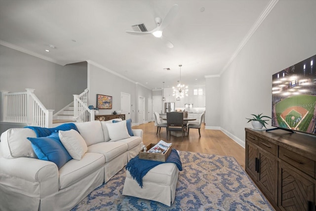 12 Country Club Ln, Belleair, FL 33756 - living area with stairway, a chandelier, light wood-style flooring, a ceiling fan, and ornamental molding