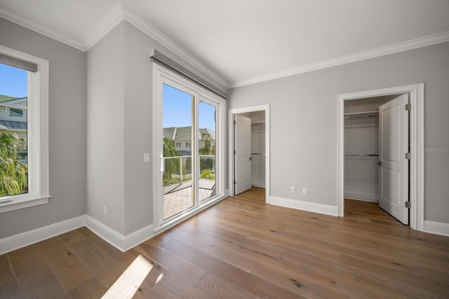 12 Country Club Ln, Belleair, FL 33756 - unfurnished bedroom with crown molding, access to exterior, baseboards, wood-type flooring, and a walk in closet