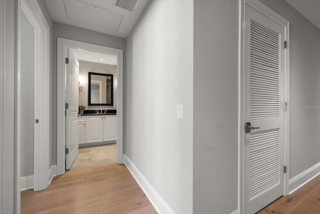 12 Country Club Ln, Belleair, FL 33756 - corridor featuring light wood-style floors, baseboards, a sink, and attic access