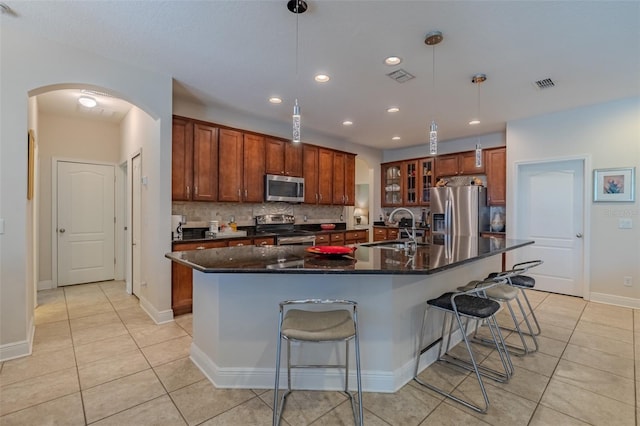 347 Cockle Shell Loop, Apollo Beach, FL 33572 - kitchen featuring stainless steel appliances, a sink, arched walkways, light tile patterned floors, and a breakfast bar area