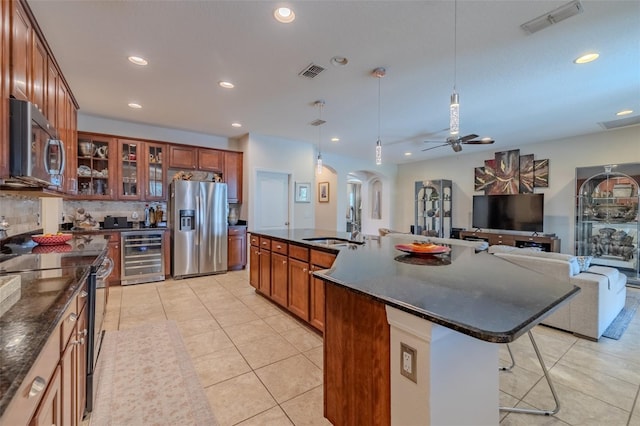 347 Cockle Shell Loop, Apollo Beach, FL 33572 - kitchen with appliances with stainless steel finishes, wine cooler, arched walkways, a kitchen bar, and light tile patterned floors